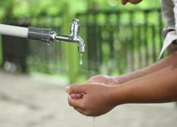 person washing hands in open faucet