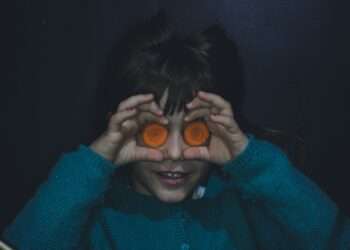 woman in green sweater covering her face with her hands