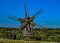 an old wooden windmill in a grassy field