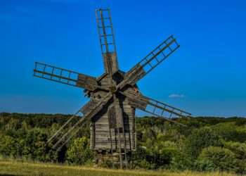 an old wooden windmill in a grassy field