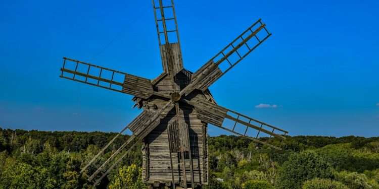an old wooden windmill in a grassy field